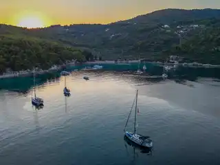 Sailing yachts anchored in a wooded bay on Alonnisos at sunset