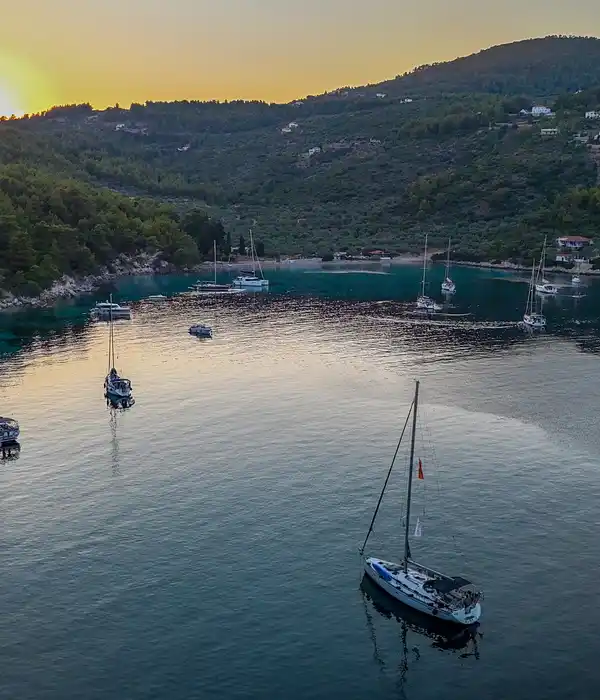 Ιστιοπλοϊκά αγκυροβολημένα σε δασωμένο όρμο της Αλοννήσου την ώρα της δύσης