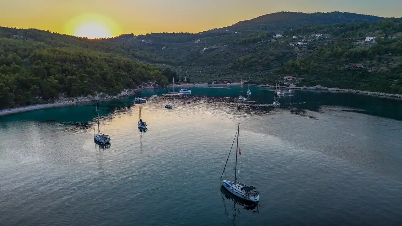 Sailing yachts anchored in a wooded bay on Alonnisos at sunset