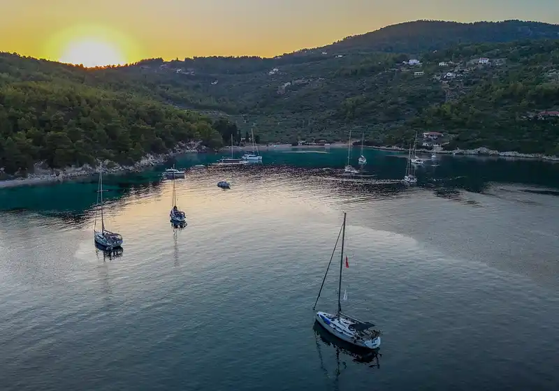 Sailing yachts anchored in a wooded bay on Alonnisos at sunset