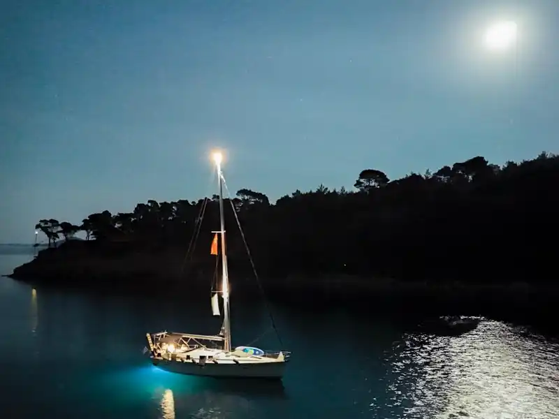 Sailing yacht lit at night under a full moon in a bay on Alonnisos