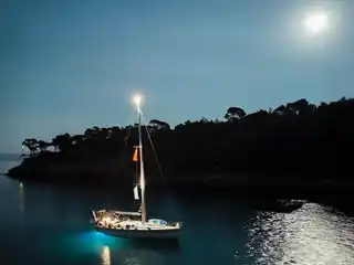 Sailing yacht lit at night under a full moon in a bay on Alonnisos