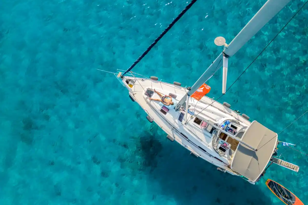 Bavaria 40 Babasails from above over turquoise water in the Sporades, a guest sunbathing on the bow