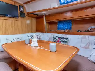Το σαλόνι του Bavaria 40 Babasails, με ξύλινο τραπέζι και λευκό καναπέ με μαξιλάρια με άγκυρες