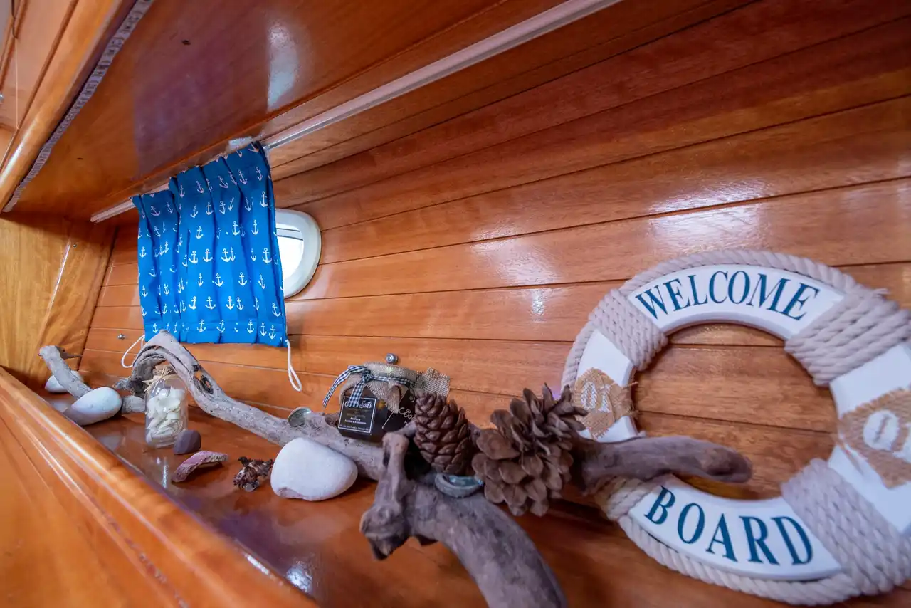 Σωσίβιο με την ευχή Welcome Aboard, θαλασσόξυλα και κουκουνάρια σε ράφι του Bavaria 40 Babasails