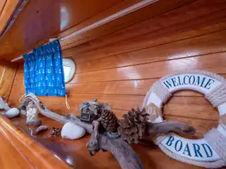 Σωσίβιο με την ευχή Welcome Aboard, θαλασσόξυλα και κουκουνάρια σε ράφι του Bavaria 40 Babasails