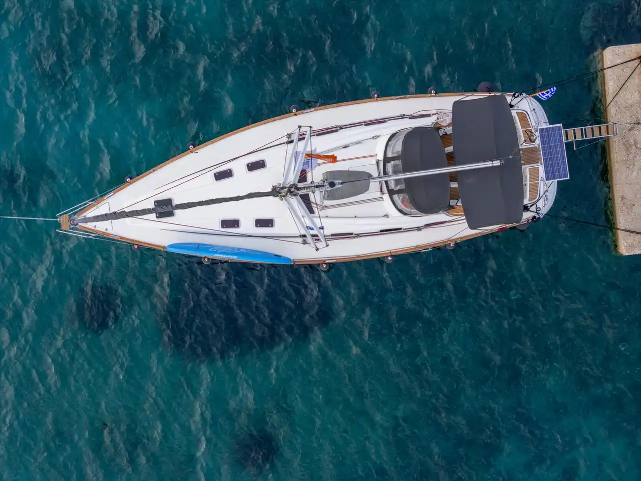 Το Bavaria 46 Fox κάθετα από ψηλά, δεμένο στον μόλο στο Παλιούρι, με μια σανίδα SUP στο κατάστρωμα