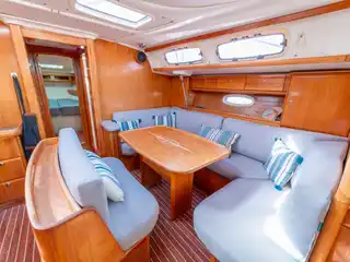 Το σαλόνι του Bavaria 46 Fox, με ξύλινο τραπέζι και γκρι καναπέδες με ριγέ μαξιλάρια