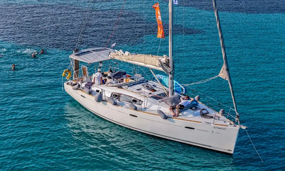 Beneteau 43 Starcat at anchor off Diaporos, guests relaxing on deck and swimming nearby