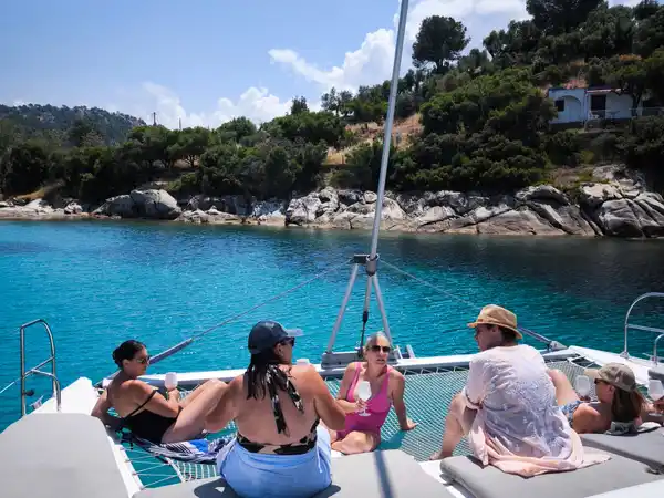 Guests relaxing on a catamaran’s bow nets in a turquoise cove