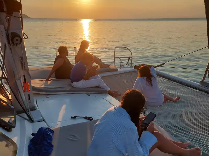 Guests watching the sunset from the bow of a catamaran
