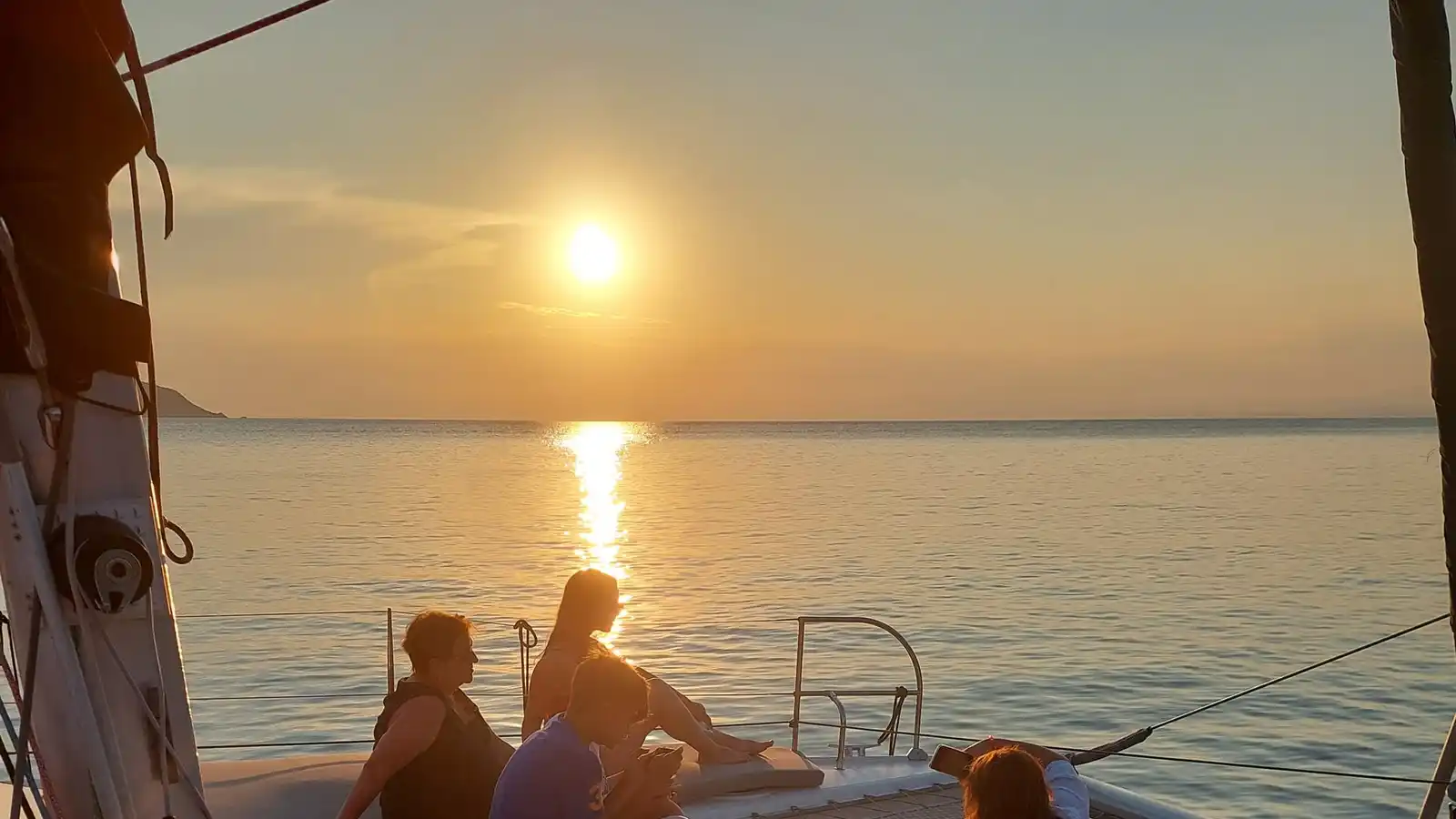 Guests watching the sunset from the bow of a catamaran