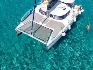 Καταμαράν στην άγκυρα σε καθαρά τιρκουάζ νερά, με κάποιον να κολυμπά δίπλα στη γάστρα