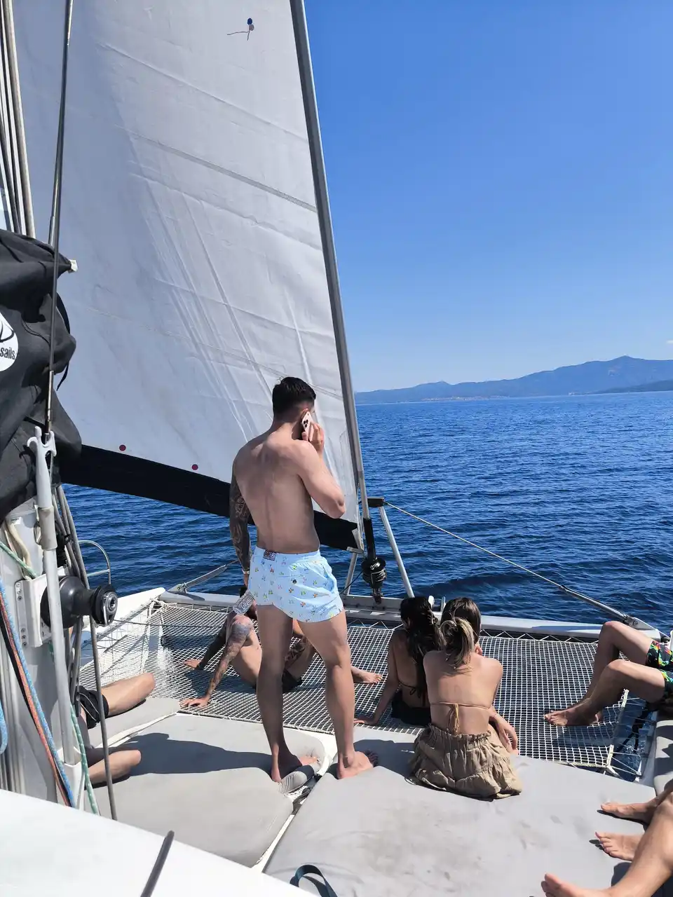 Guests relaxing on a catamaran’s bow under sail on open water