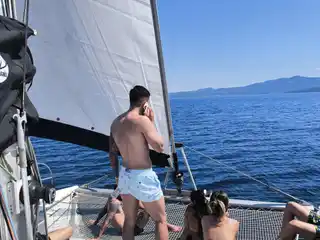 Guests relaxing on a catamaran’s bow under sail on open water