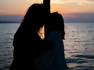Silhouette of a couple embracing on a yacht as the sun sets over the sea