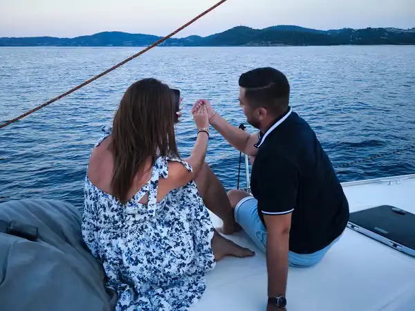 Couple sharing a toast on a sailing yacht’s bow at dusk