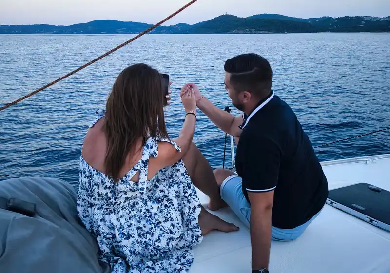 Couple sharing a toast on a sailing yacht’s bow at dusk