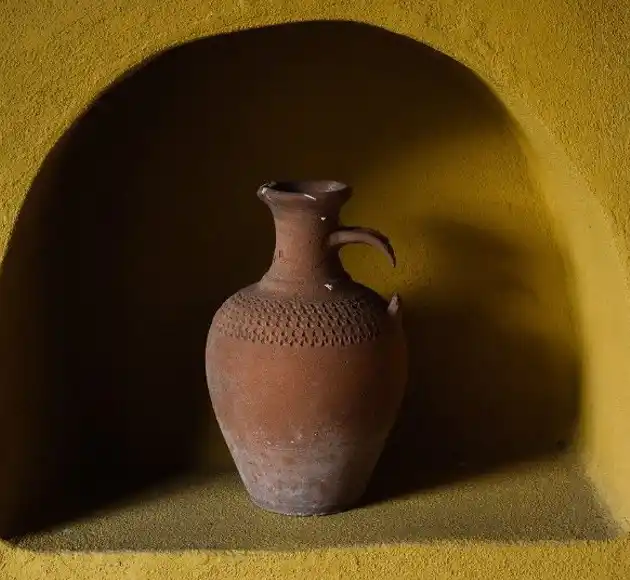 Clay jug with a carved pattern in a yellow wall niche