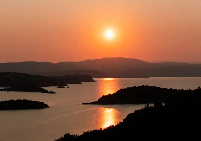 Ο ήλιος δύει πάνω από τις νησίδες του Διάπορου και καθρεφτίζεται στο ήρεμο νερό