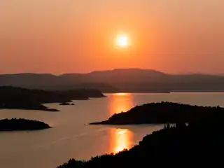 Sun setting over the islets of Diaporos, reflected on calm water