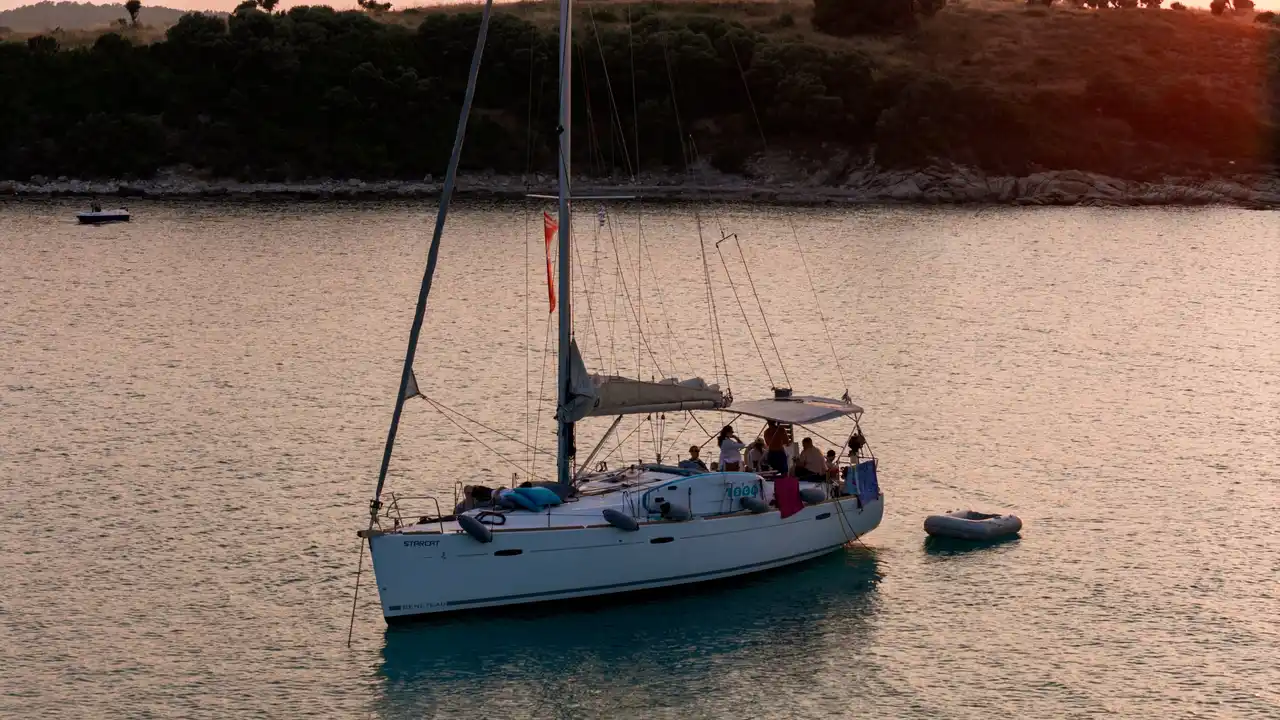 Guests on a sailing yacht at anchor off Diaporos in warm evening light