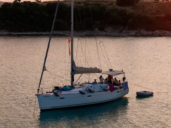 Guests on a sailing yacht at anchor off Diaporos in warm evening light