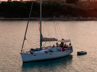 Guests on a sailing yacht at anchor off Diaporos in warm evening light