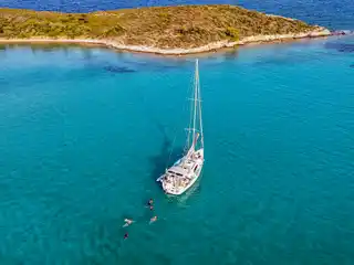 Ιστιοπλοϊκό δίπλα σε χαμηλή νησίδα κοντά στον Διάπορο, με επιβάτες να κολυμπούν