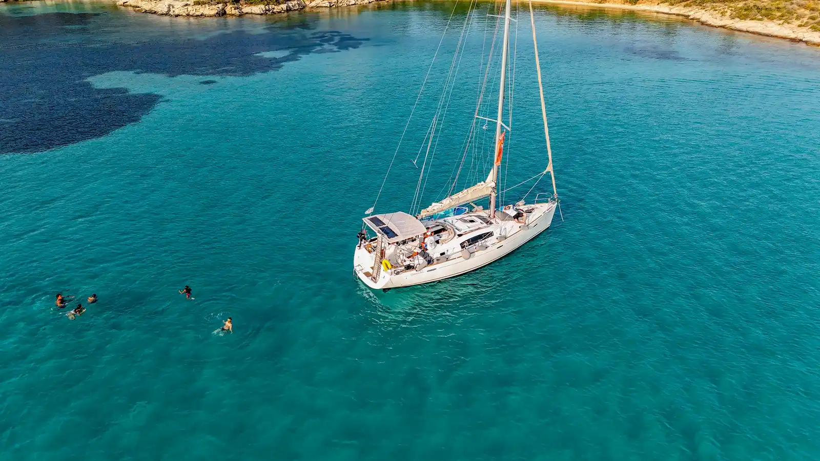 Guests swimming by a sailing yacht off Diaporos