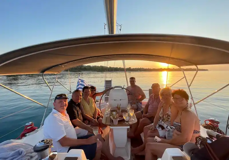 Group of friends smiling in a sailing yacht’s cockpit at sunset
