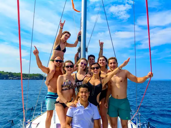 Group of friends posing and cheering on the bow of a sailing yacht