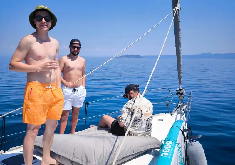 Friends standing on a sailing yacht’s bow on a calm blue sea