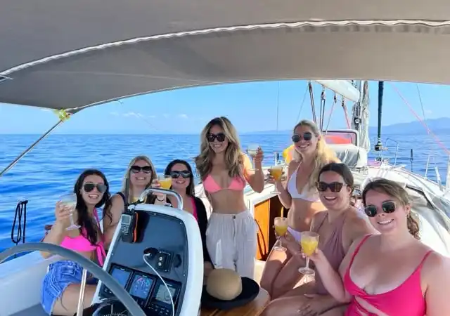 Group of friends raising drinks in a sailing yacht’s cockpit
