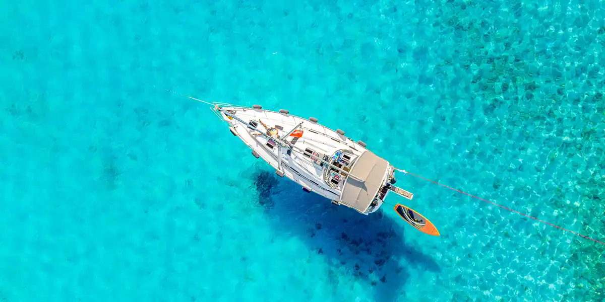 Sailing yacht over bright turquoise shallows, seen from above