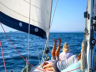 Επιβάτες ξαπλωμένοι στο κατάστρωμα ιστιοπλοϊκού, κάτω από τον φλόκο, στα ανοιχτά