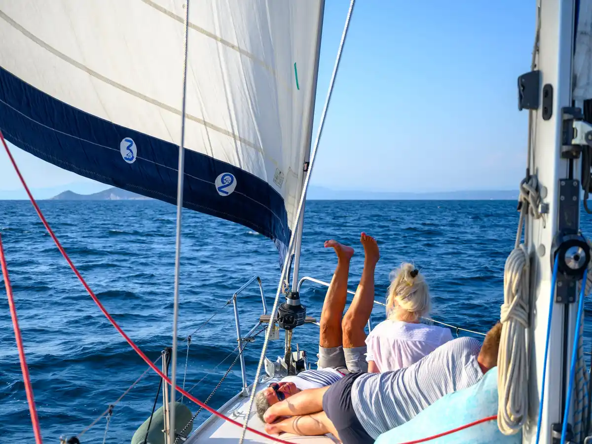 Επιβάτες ξαπλωμένοι στο κατάστρωμα ιστιοπλοϊκού, κάτω από τον φλόκο, στα ανοιχτά