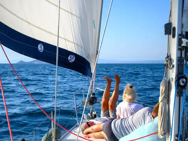 Επιβάτες ξαπλωμένοι στο κατάστρωμα ιστιοπλοϊκού, κάτω από τον φλόκο, στα ανοιχτά