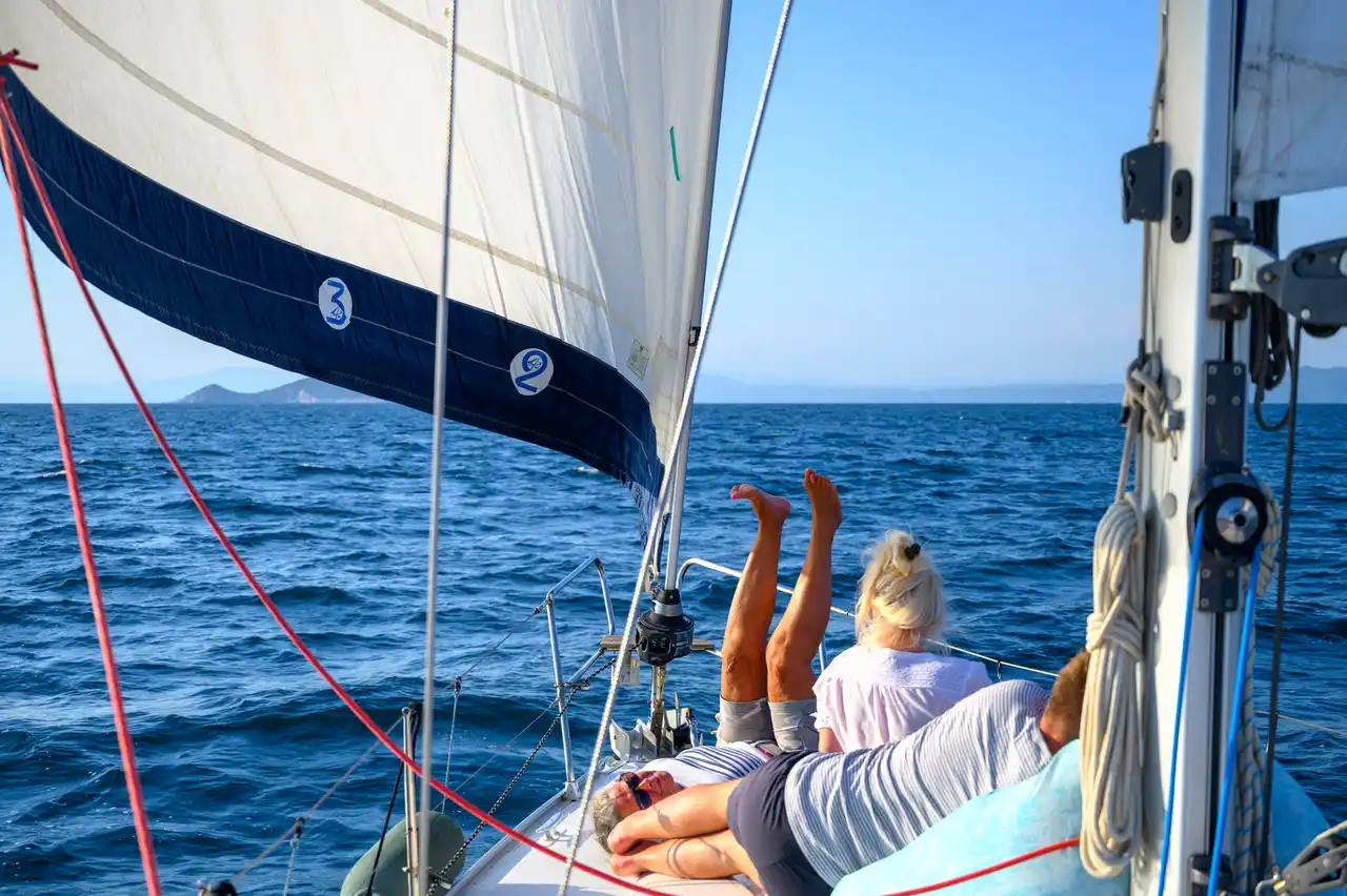 Επιβάτες ξαπλωμένοι στο κατάστρωμα ιστιοπλοϊκού, κάτω από τον φλόκο, στα ανοιχτά