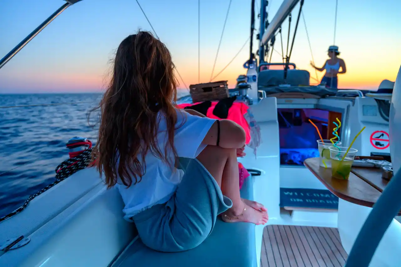 Orange sky over guests on the deck of a sailing yacht at sunset