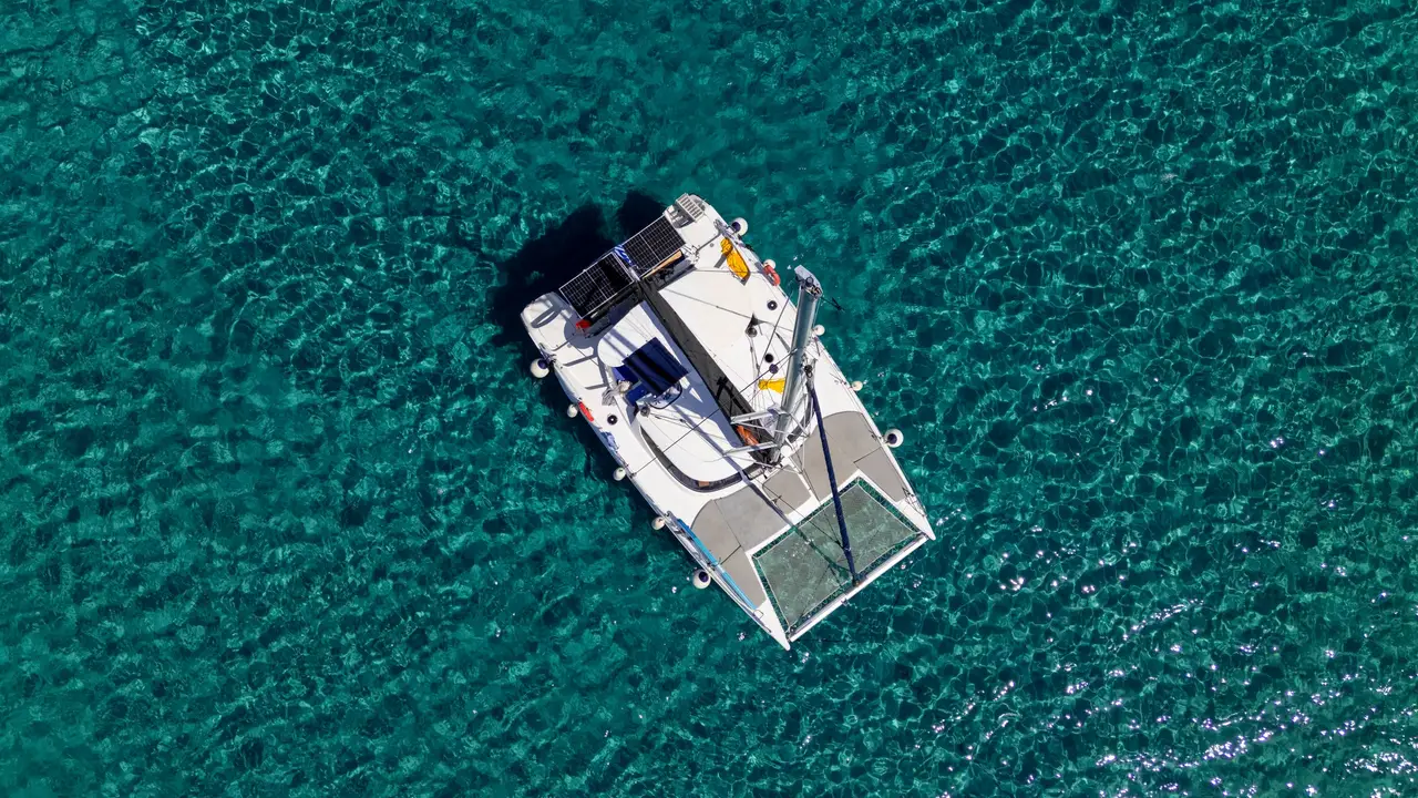 Καταμαράν μόνο του στην άγκυρα σε τιρκουάζ νερά με κυματάκια, από ψηλά, Κασσάνδρα