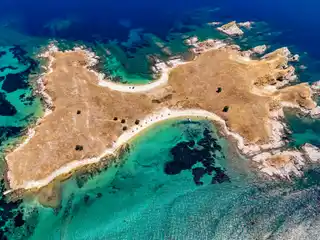Small sunburnt islet near Ouranoupoli with two sandy beaches and turquoise shallows