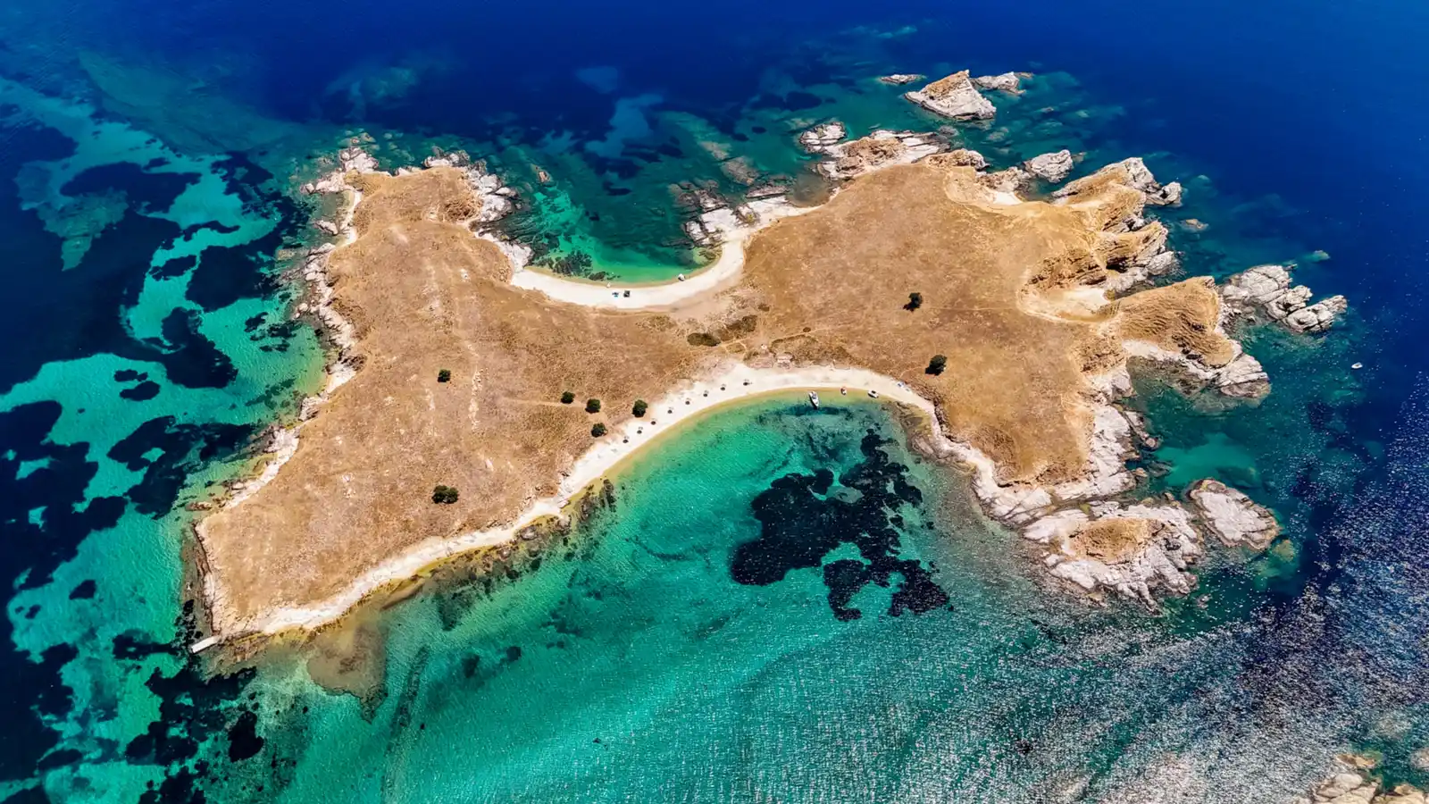 Small sunburnt islet near Ouranoupoli with two sandy beaches and turquoise shallows