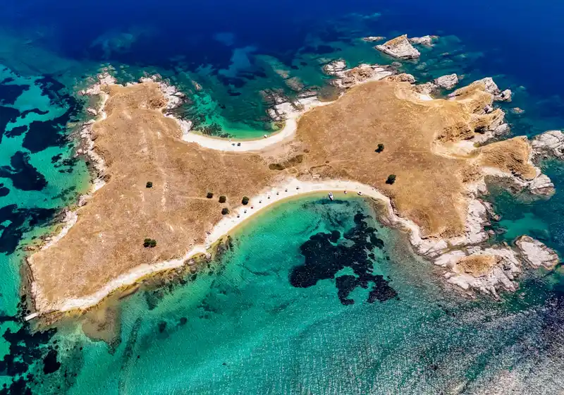 Μικρή ηλιοκαμένη νησίδα κοντά στην Ουρανούπολη, με δύο αμμουδιές και ρηχά τιρκουάζ νερά