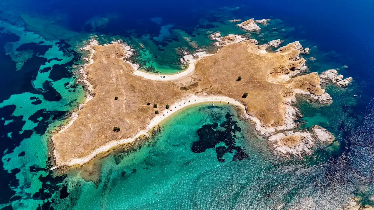 Small sunburnt islet near Ouranoupoli with two sandy beaches and turquoise shallows