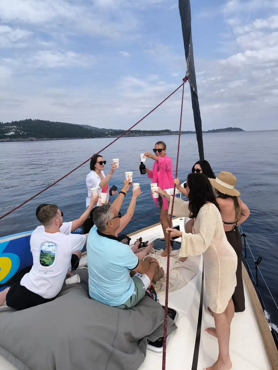 Friends toasting on the bow of a sailing yacht off Kassandra
