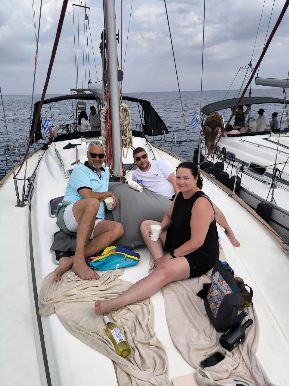 Guests relaxing on the bow of a sailing yacht beside another yacht off Kassandra