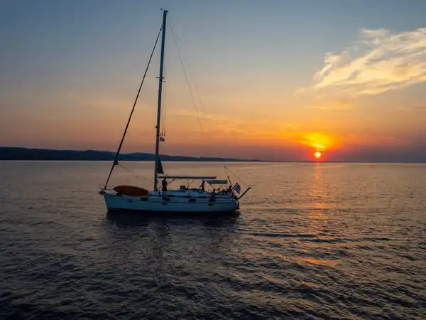 Sailing yacht at anchor off Kassandra at sunset, the sun sinking to the horizon