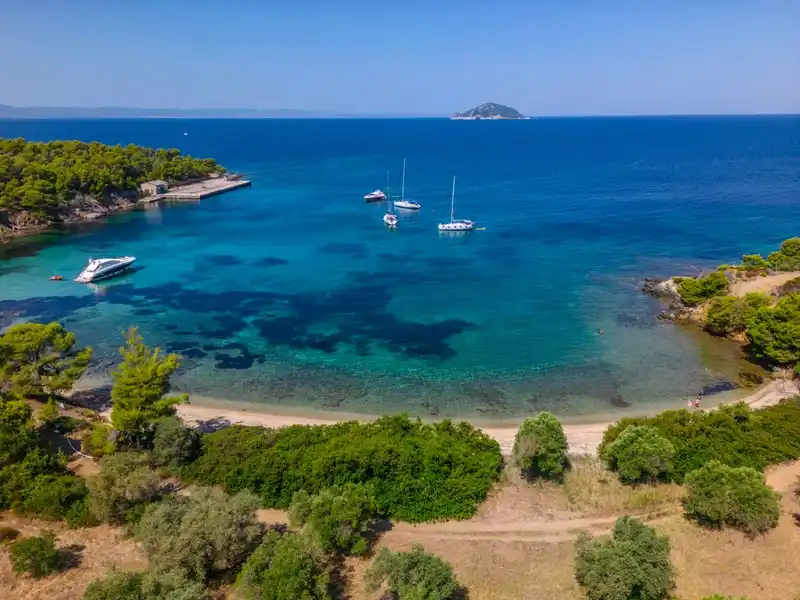 Sailing yachts anchored near Porto Carras, an islet on the horizon