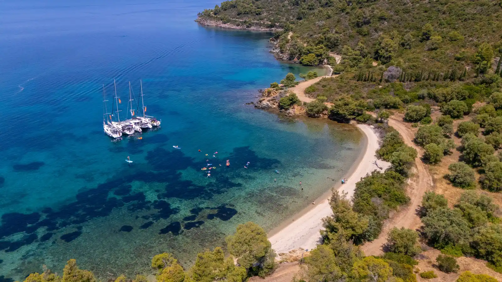 Ιστιοπλοϊκά δεμένα μαζί σε ήσυχο όρμο κοντά στο Πόρτο Καρράς, με επιβάτες να κολυμπούν